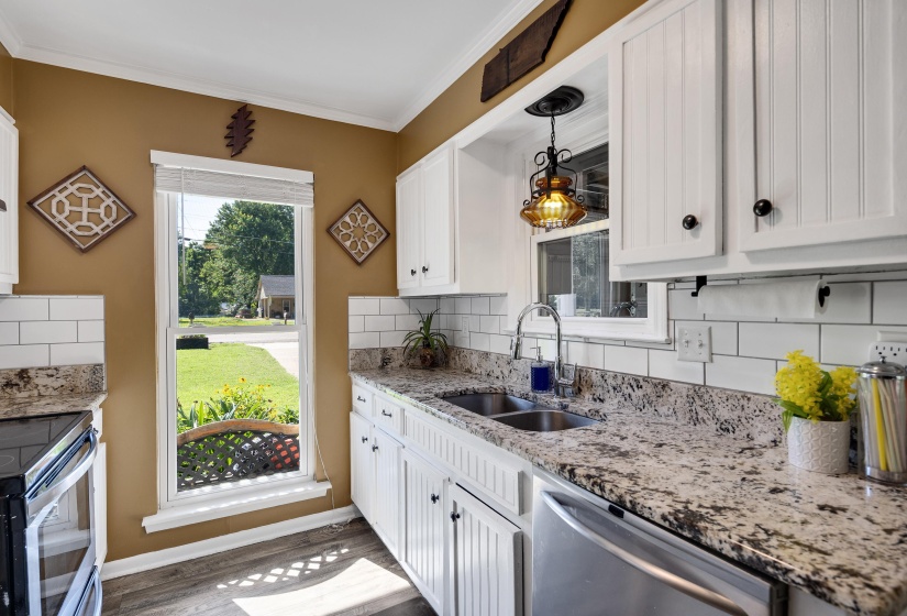 Kitchen featuring white cabinetry, granite-style countertops, subway tile backsplash, stainless steel appliances