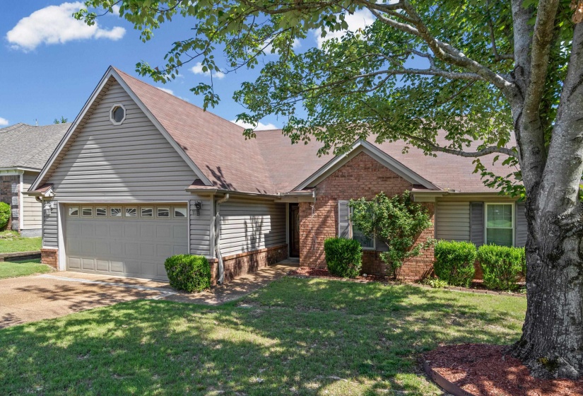 Traditional-style residence featuring a brick and siding facade, an attached two-car garage with panel windows, and a gabled roof
