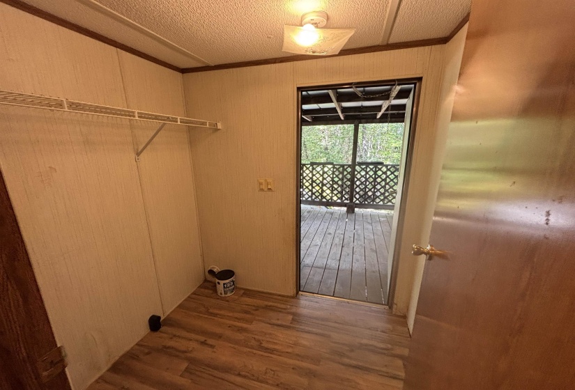 Washroom featuring dark wood-type flooring, wood walls, a textured ceiling, and ornamental molding