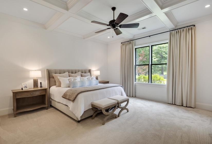 Recessed lighting illuminates a coffered ceiling with a central ceiling fan