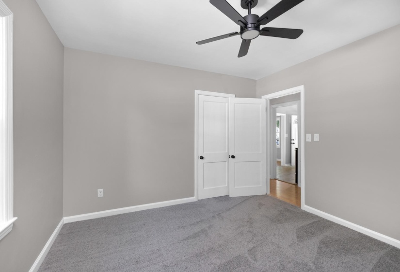 Room featuring neutral gray wall paint, gray carpet flooring, white trim, and a black ceiling fan