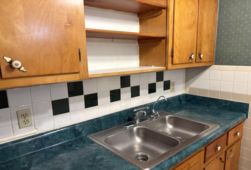 Kitchen featuring decorative backsplash, dark countertops, brown cabinetry, and open shelves