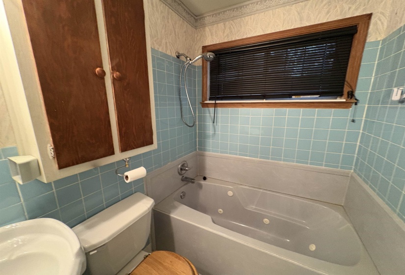Full bathroom featuring tile walls and a combined bath / shower with jetted tub