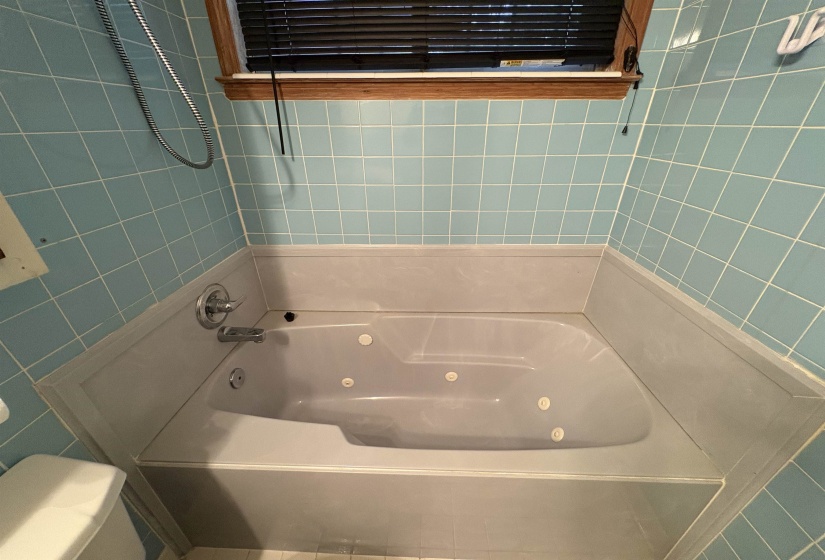 Full bathroom with a combined bath / shower with jetted tub and tile walls