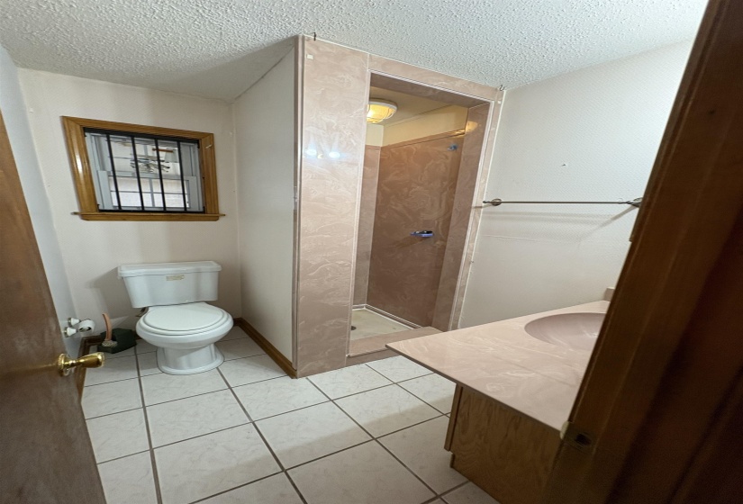 Bathroom with a stall shower, vanity, light tile patterned floors, and a textured ceiling