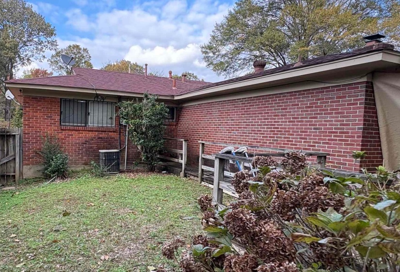 Rear view of house featuring brick siding and a fenced backyard