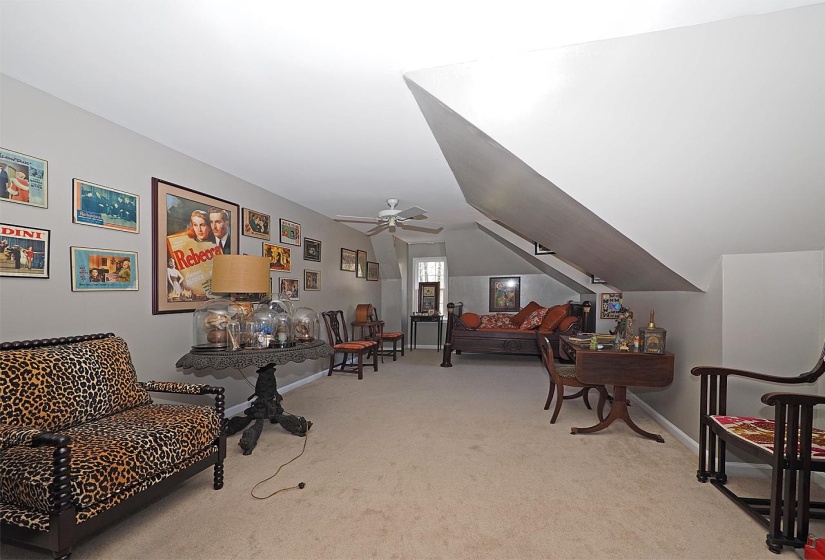 Living area with light carpet, vaulted ceiling, and a ceiling fan