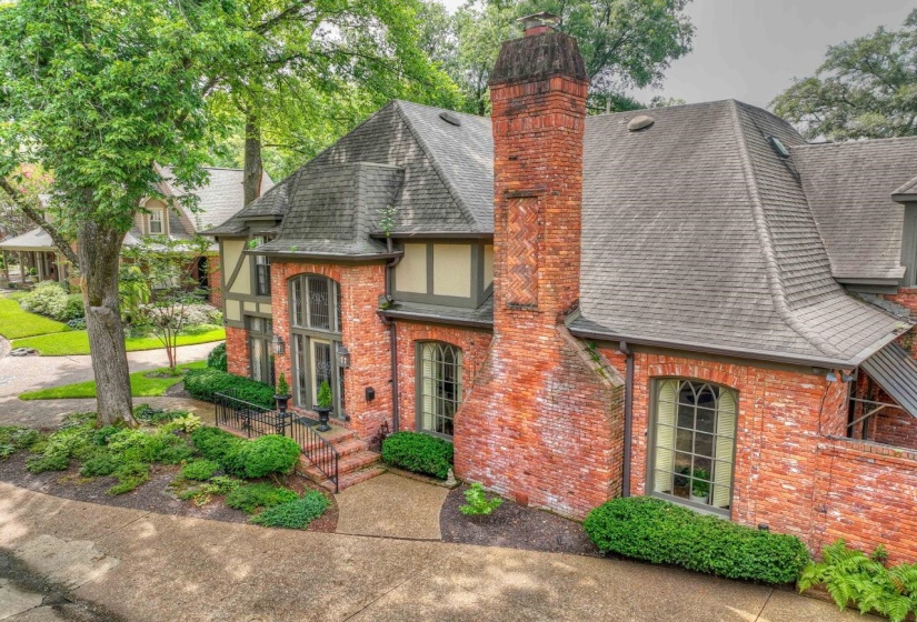 Tudor house with a shingled roof, a chimney, and brick siding