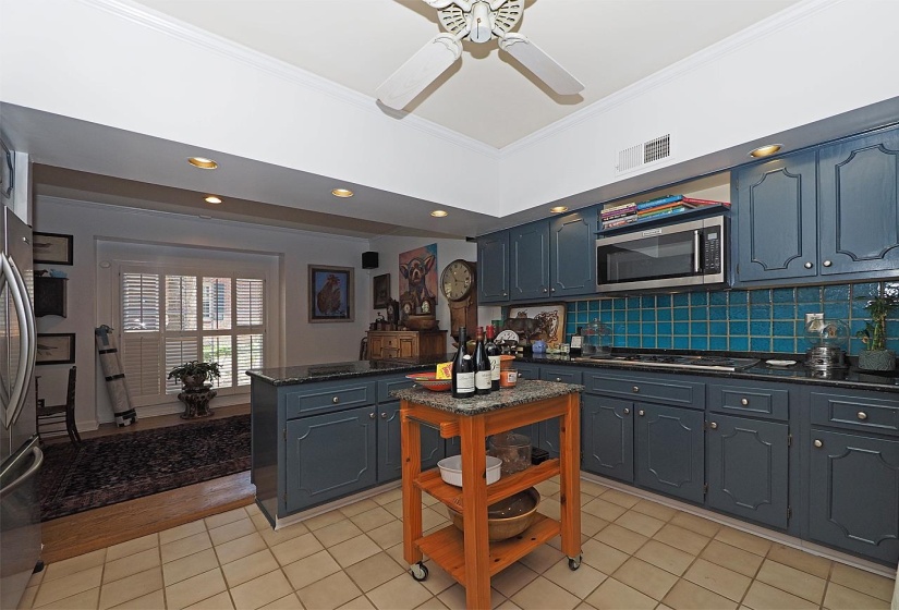 Kitchen featuring dark stone countertops, crown molding, stainless steel appliances, decorative backsplash, and light tile patterned floors