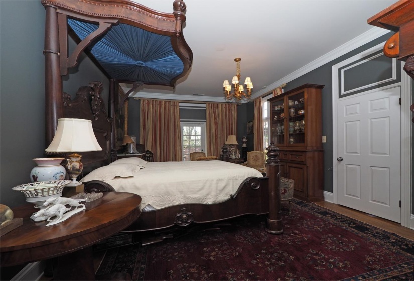 Bedroom featuring crown molding, suspended lighting, and dark wood-style flooring