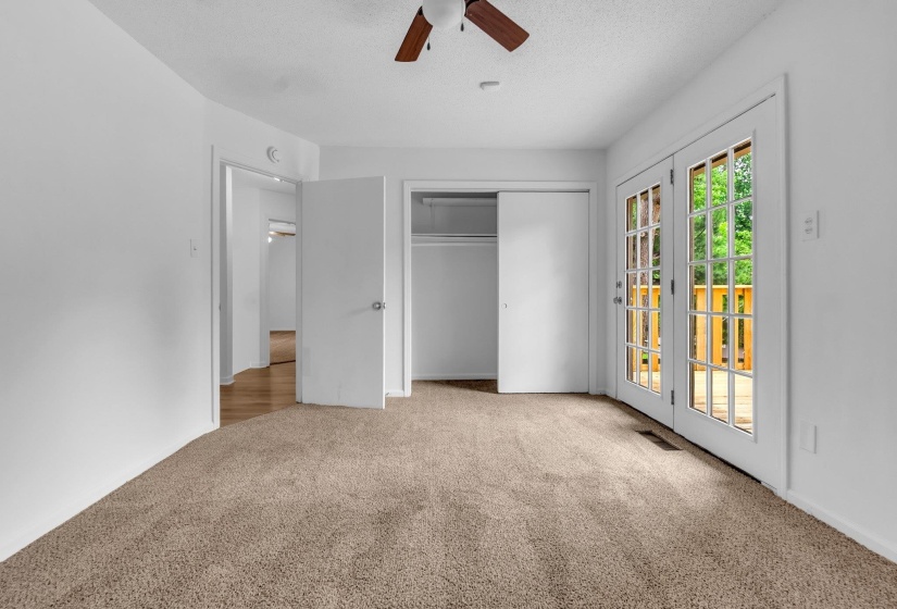 Carpeted room featuring a ceiling fan, white walls, and a closet with sliding doors