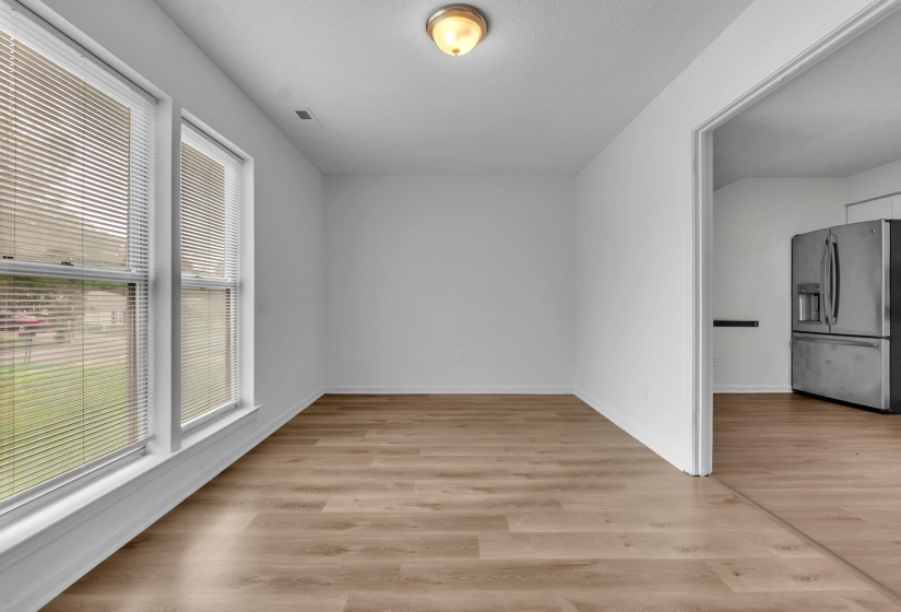 Spacious room featuring wood-finish flooring, white walls, and a ceiling-mounted light fixture