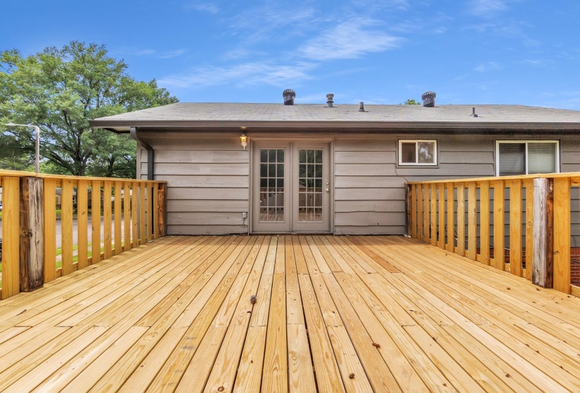 Spacious wood deck with natural wood railing and privacy wall