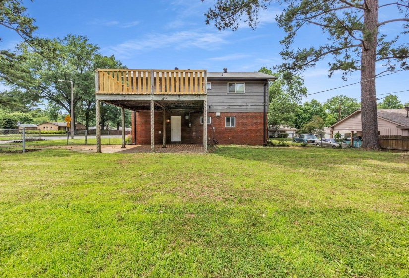 Two-story residence featuring a wood deck with railing, a red brick lower level, and light-colored siding on the upper level