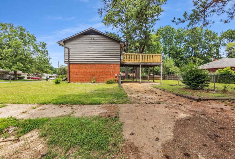 Rear exterior featuring a raised wooden deck, a brick foundation, and horizontal siding