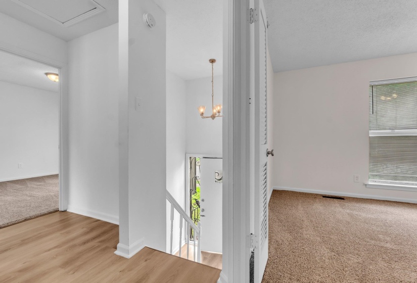 Entryway featuring a decorative chandelier, white spindle staircase, and wood-finish flooring