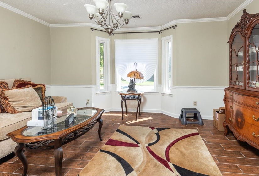 Living area featuring wood tiled floors, crown molding, a textured ceiling, and a chandelier