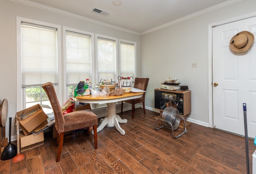 Dining room with ornamental molding and dark wood-type flooring
