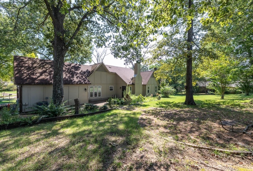 Rear view of house featuring a lawn, a chimney, board and batten siding, and roof with shingles