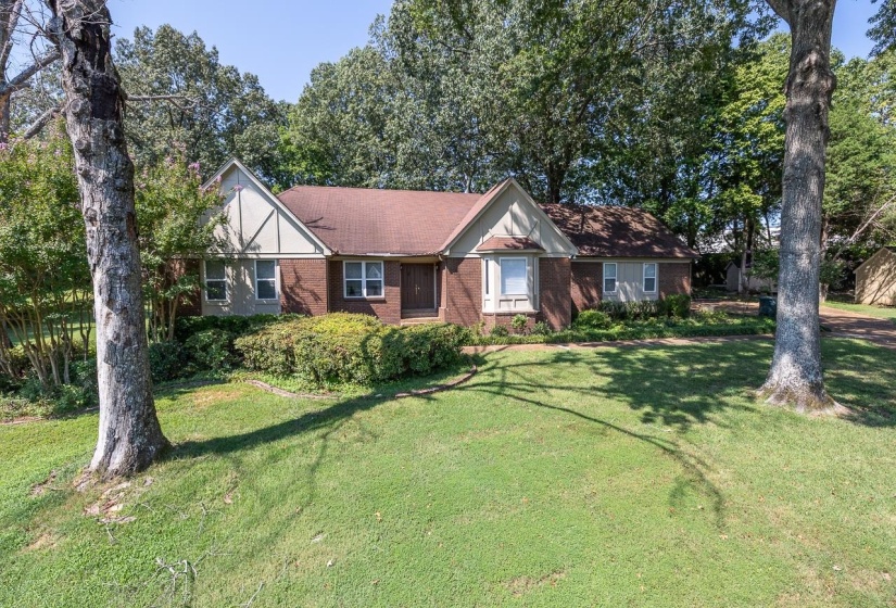 View of front of house with a front yard, brick siding, and roof with shingles