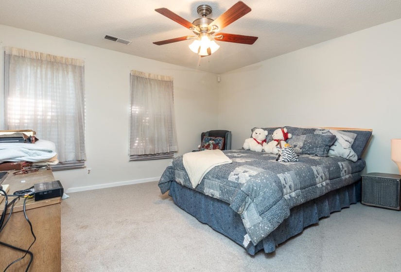 Carpeted bedroom featuring a ceiling fan and a textured ceiling