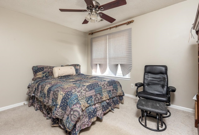 Bedroom with a textured ceiling, light colored carpet, and ceiling fan