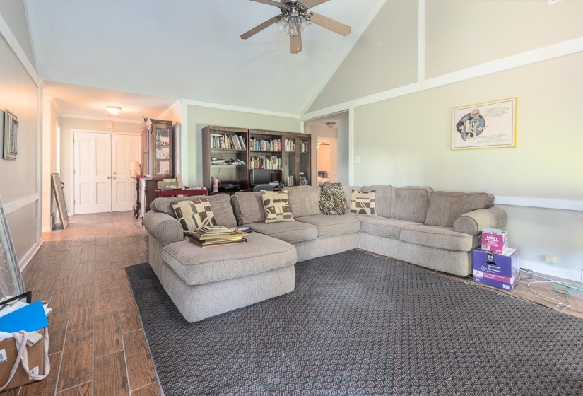 Living room featuring high vaulted ceiling, dark wood-type flooring, a ceiling fan, and crown molding