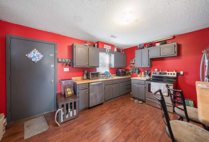 Kitchen featuring light countertops, gray cabinets, stainless steel appliances, dark wood-style floors, and a textured ceiling