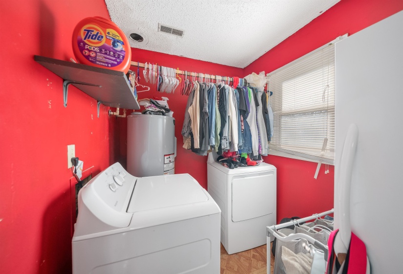 Laundry room featuring electric water heater, washing machine and clothes dryer, and a textured ceiling