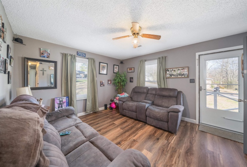 Living area featuring a textured ceiling, wood finished floors, and ceiling fan