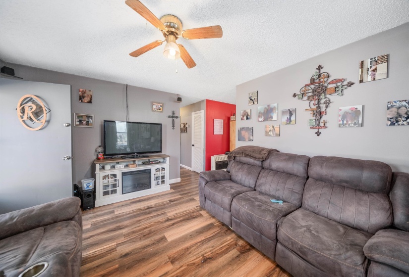 Living room featuring a textured ceiling, wood finished floors, and ceiling fan