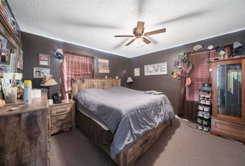 Carpeted bedroom with a textured ceiling and a ceiling fan