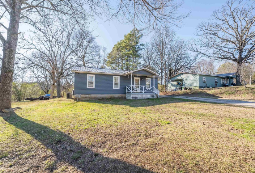 View of front facade featuring a metal roof, a front yard, and a deck