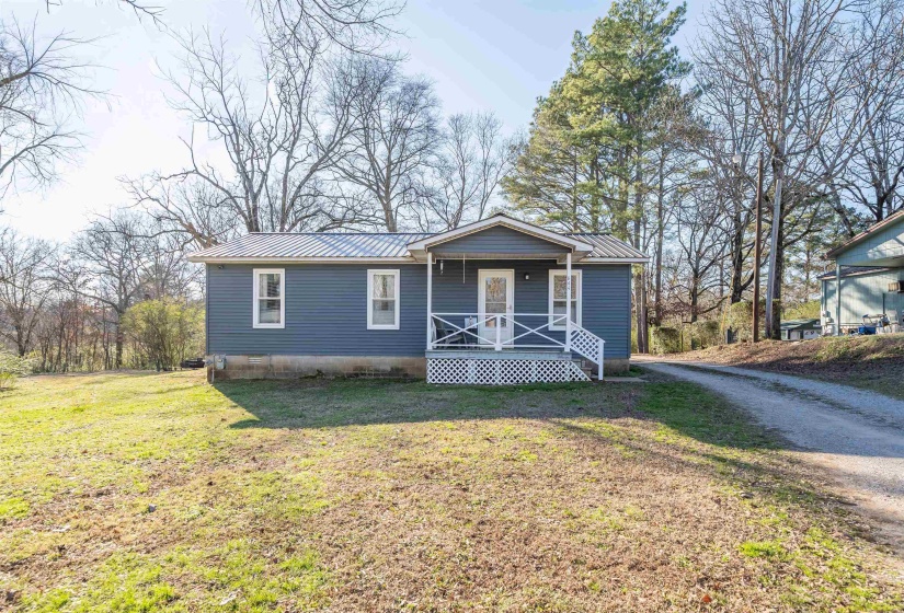 View of front of house featuring a metal roof, a front yard, a porch, crawl space, and driveway