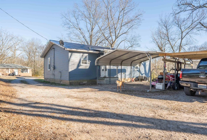 View of property exterior with crawl space, a metal roof, a detached carport, and driveway