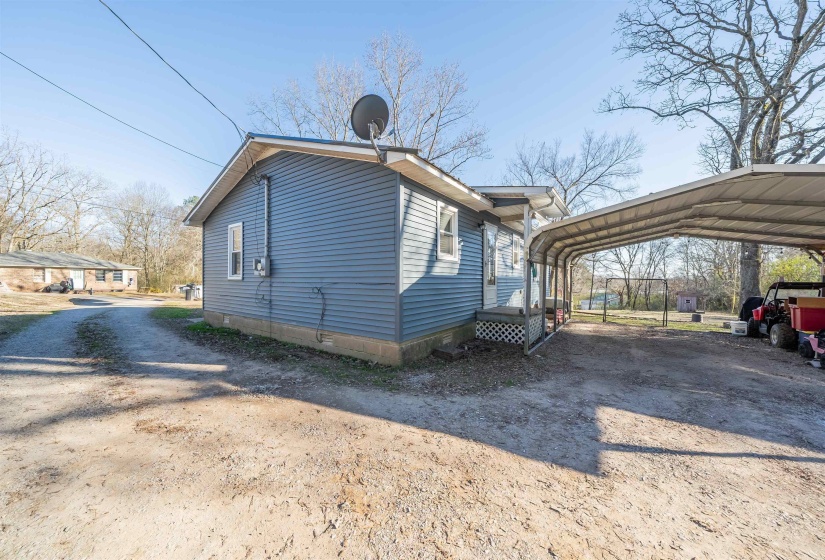 View of home's exterior with a carport and dirt driveway