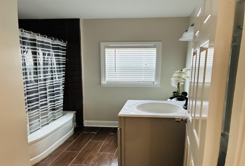 Full bathroom featuring vanity, wood tiled floors, and shower / bathtub combination with curtain
