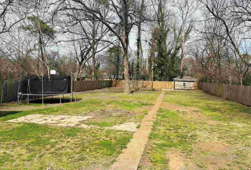 Fenced backyard with an outdoor structure and a trampoline