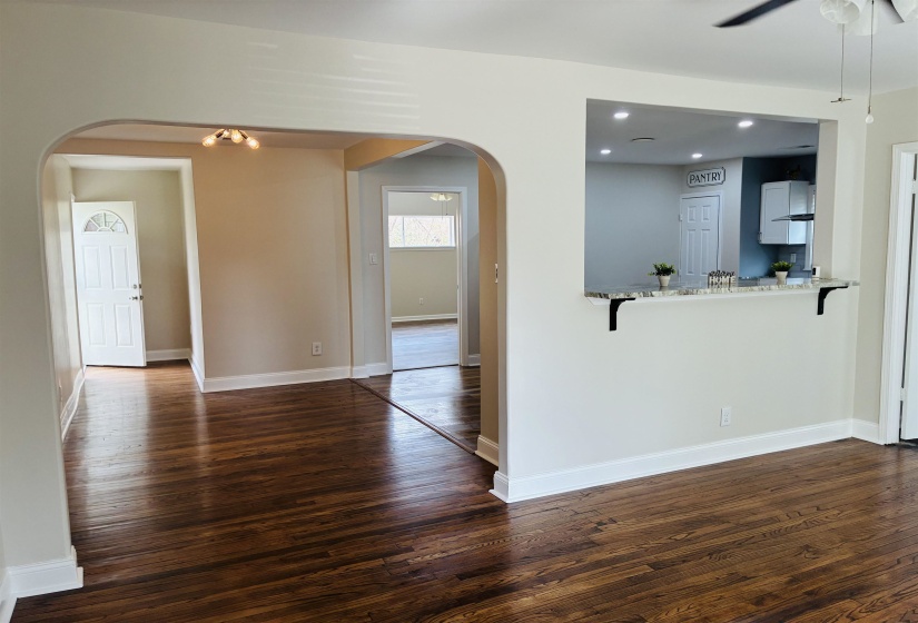 Unfurnished living room featuring dark wood finished floors, arched walkways, a ceiling fan, and recessed lighting
