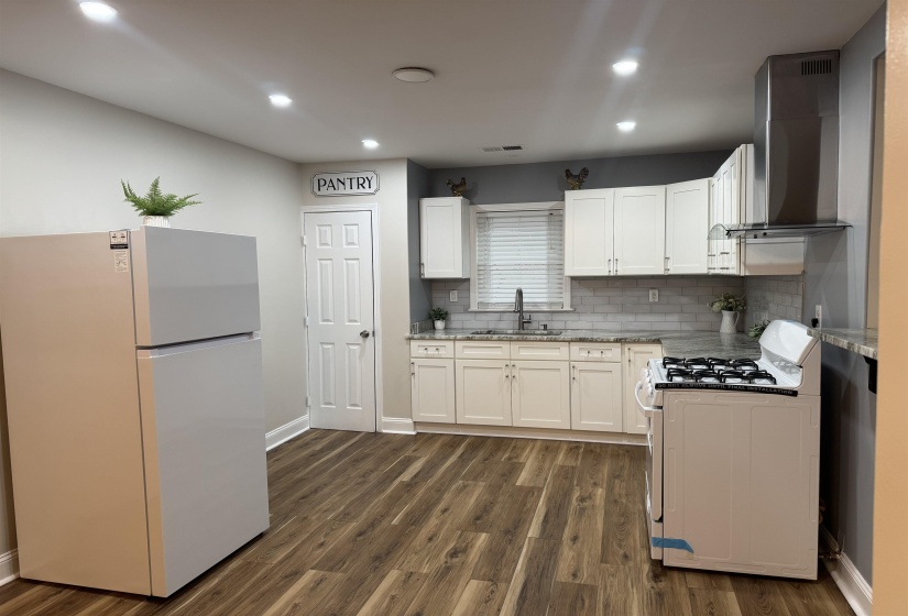 Kitchen featuring white appliances, white cabinetry, dark wood-style floors, light stone countertops, and recessed lighting