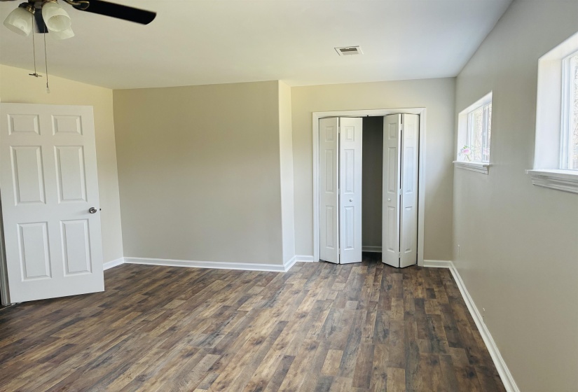 Unfurnished bedroom with dark wood-style floors, a closet, and ceiling fan