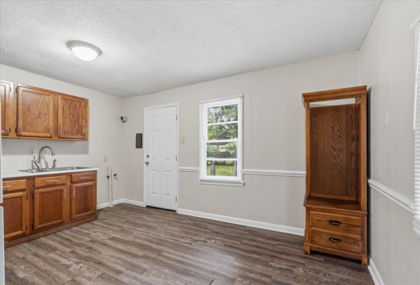 Functional kitchen area with wood-finish flooring, wood cabinetry, stainless steel sink, and light gray walls