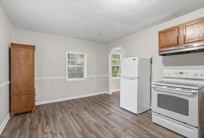 Kitchen space featuring wood-finish flooring, white appliances, and warm-toned cabinetry