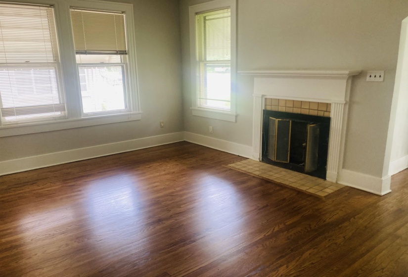 Interior space featuring wood-finish flooring, a decorative fireplace with a tile surround and hearth, and multiple windows