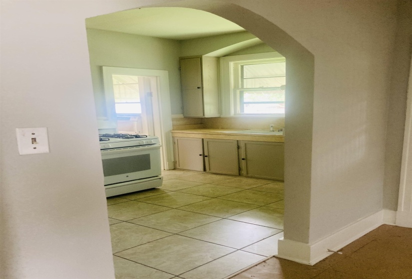 Kitchen featuring an arched doorway, tiled flooring, built-in cabinetry, a window over the sink, and a white freestanding range