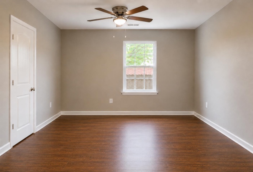 Room featuring wood-finish flooring, a ceiling fan with integrated lighting, a double-hung window, and a white interior door with a paneled design