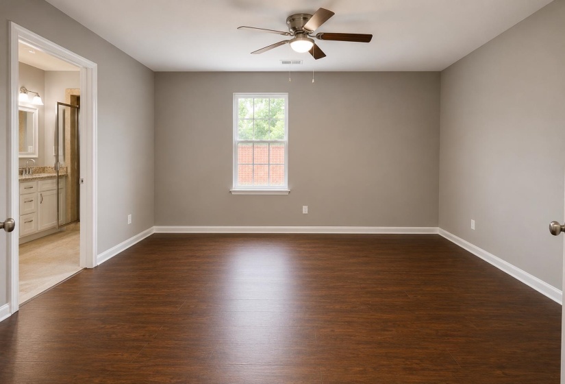 Spacious room featuring wood-finish flooring, neutral wall tones, and a ceiling fan with integrated lighting