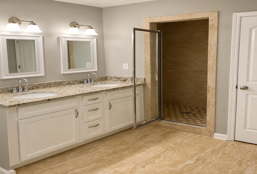 Bathroom featuring a dual vanity with a granite countertop, undermount sinks, and white cabinetry