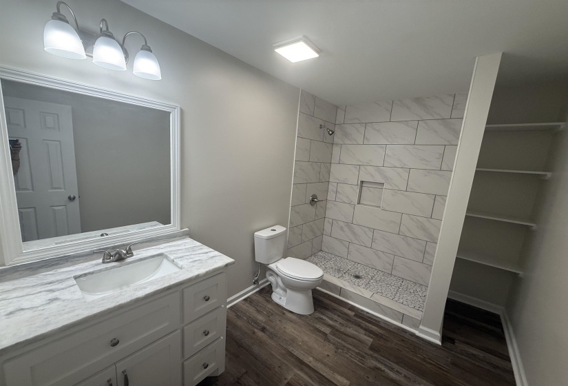 Bathroom featuring a white vanity with an integrated sink, a marble-patterned countertop, and a framed mirror