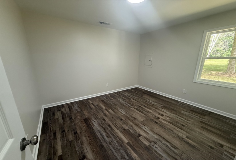 Room featuring wood-finish flooring, white baseboards, and neutral wall tones